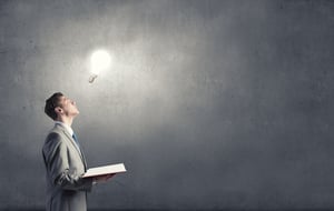 Businessman holding opened book with glass glowing light bulb