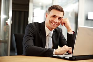 Smiling businessman sitting with laptop at office